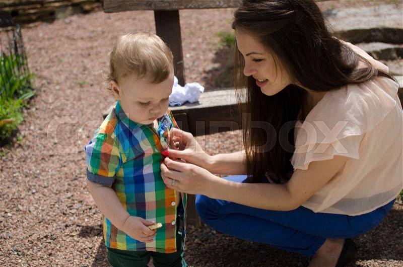 Young mother changes clothes for her small baby boy, stock photo
