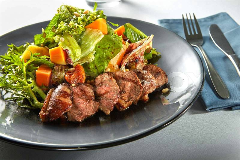 Delicious, grilled meat duck with roasted pumpkin and fresh green herb salad on a plate, stock photo
