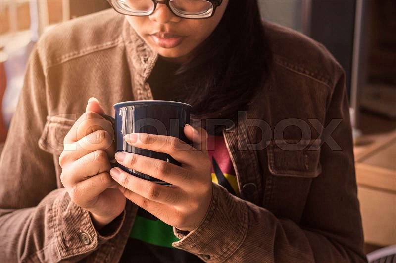Young girl holding a cup of coffee at work, stock photo
