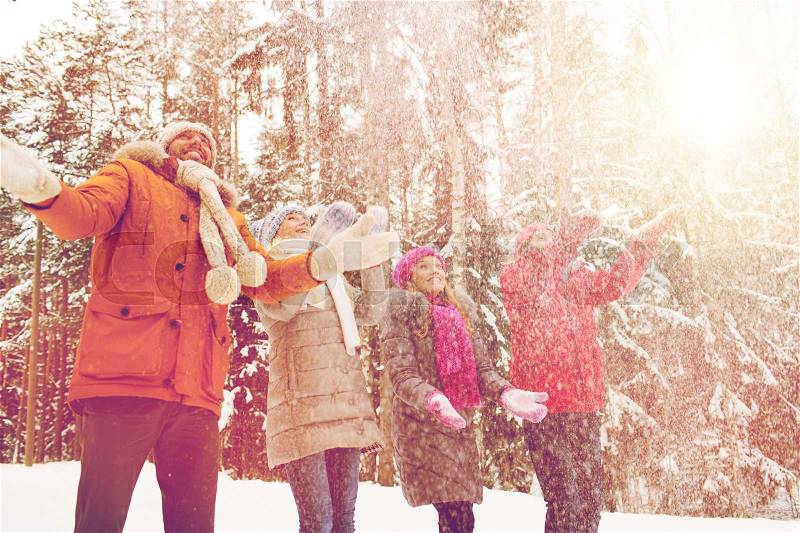 Christmas, season, friendship and people concept - group of smiling men and women having fun and playing with snow in winter forest, stock photo