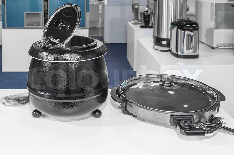 Electrical kitchen equipment, electric pressure cooker and frying pan in the foreground, stock photo