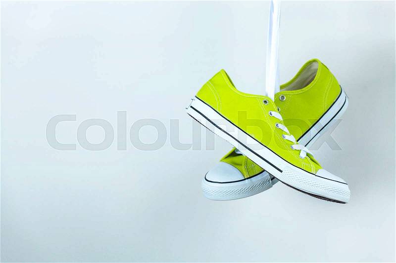 Pair of new green sneakers hanging on the wall, stock photo