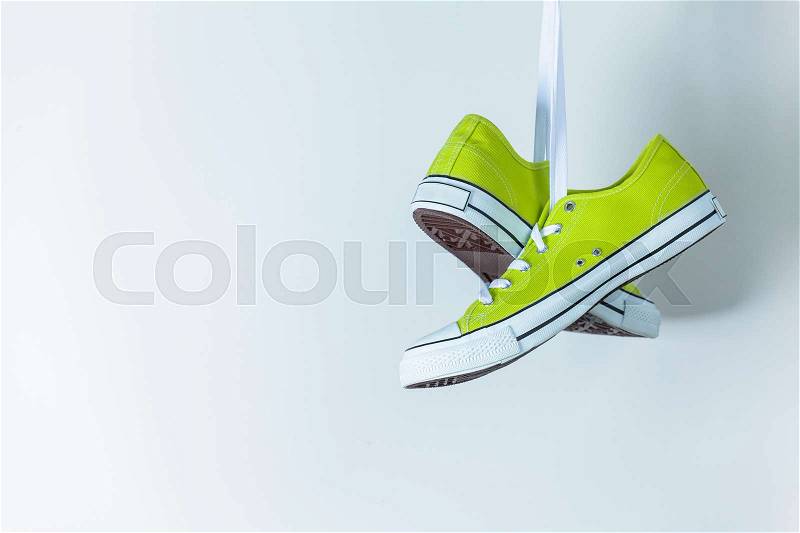 Pair of new green sneakers hanging on the wall, stock photo