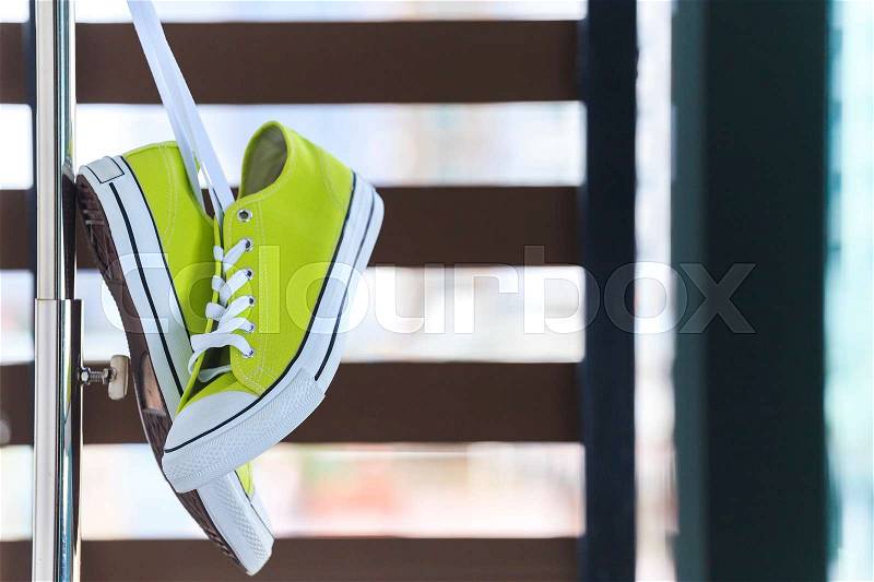 Pair of new green sneakers hanging on clothes line, stock photo