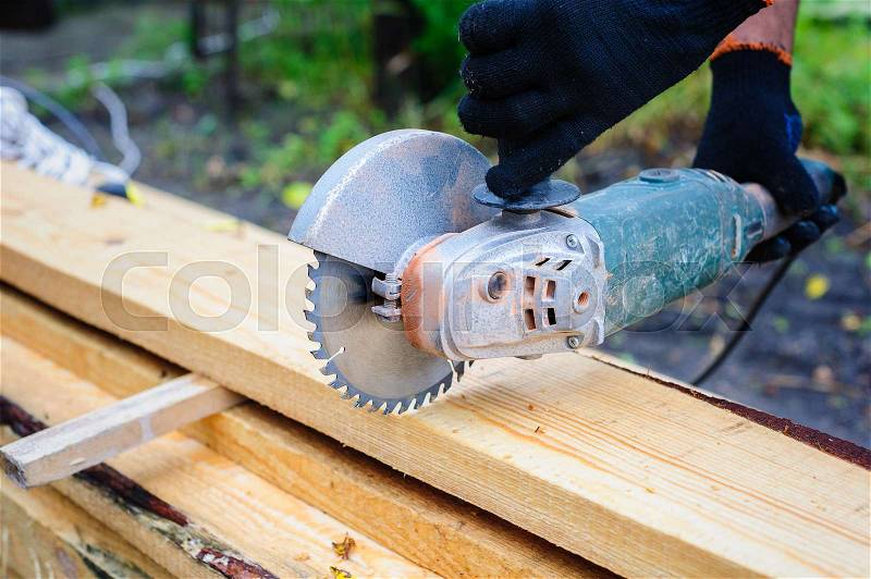 Men Use Hand Held Power Saw to Cut Planks of Wood for Home Construction, stock photo