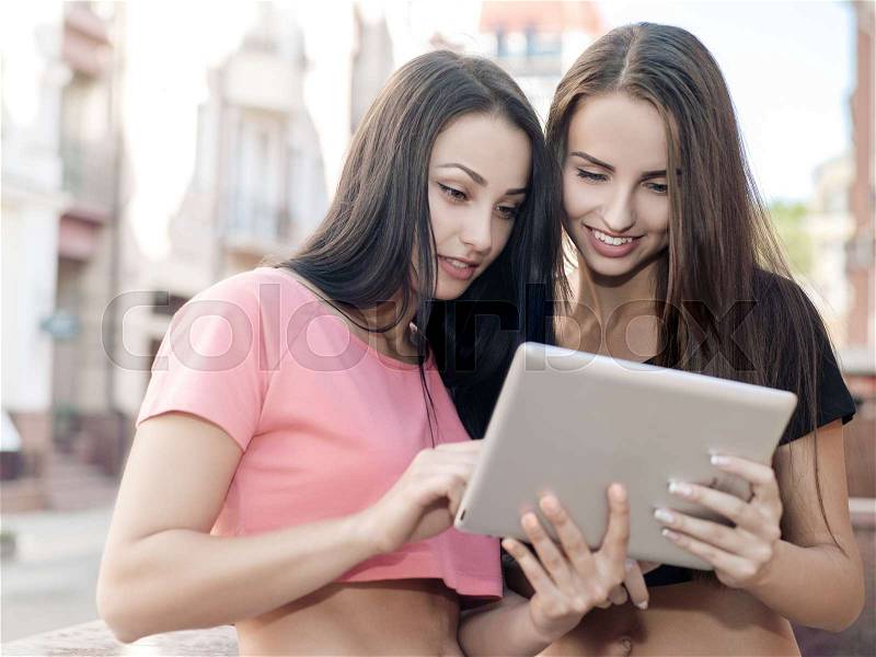 Young pretty girls looking in the tablet, female urban portrait, stock photo