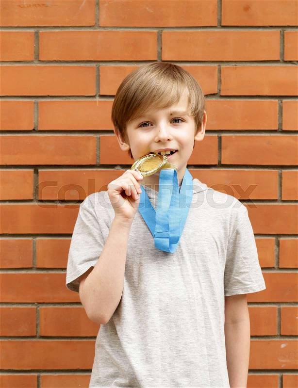 Blond boy is happy gold medal - champion, winner, stock photo