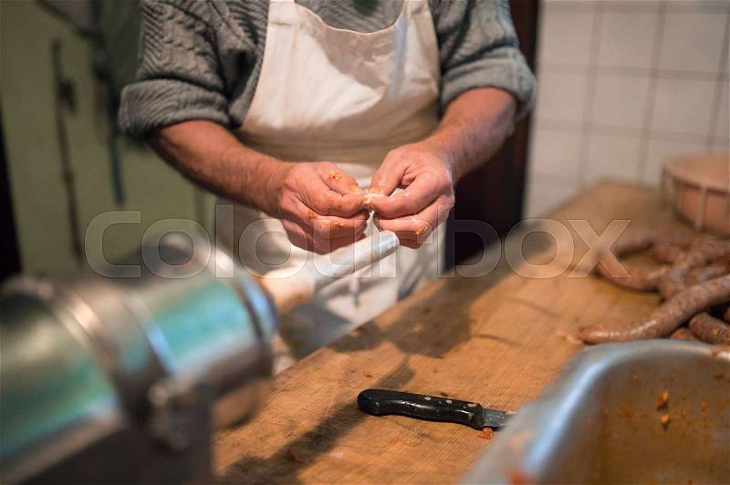 Unrecognizable man making sausages the traditional way using sausage filler. Homemade sausage, stock photo