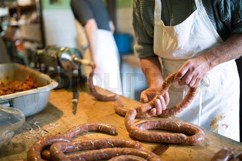 Two unrecognizable men making sausages the traditional way using sausage filler. Homemade sausage, stock photo