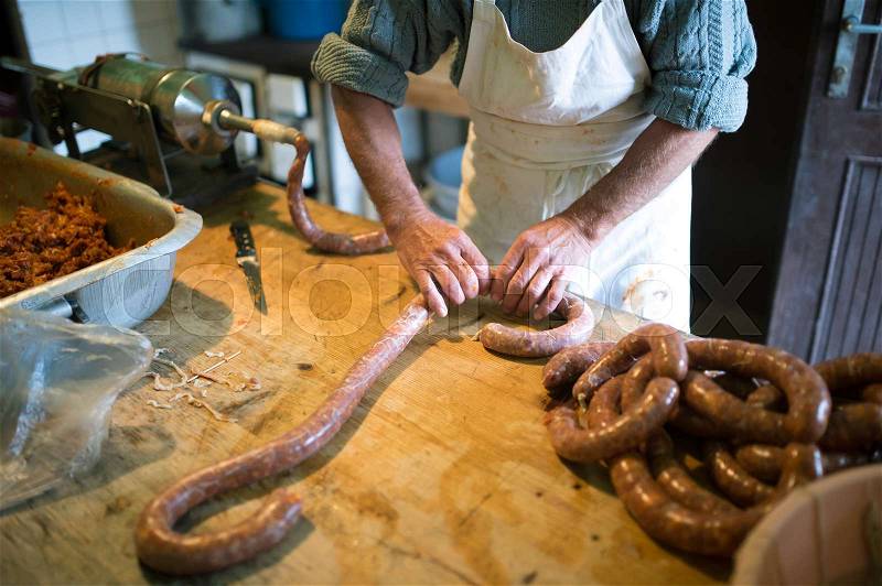 Unrecognizable man making sausages the traditional way using sausage filler. Homemade sausage, stock photo