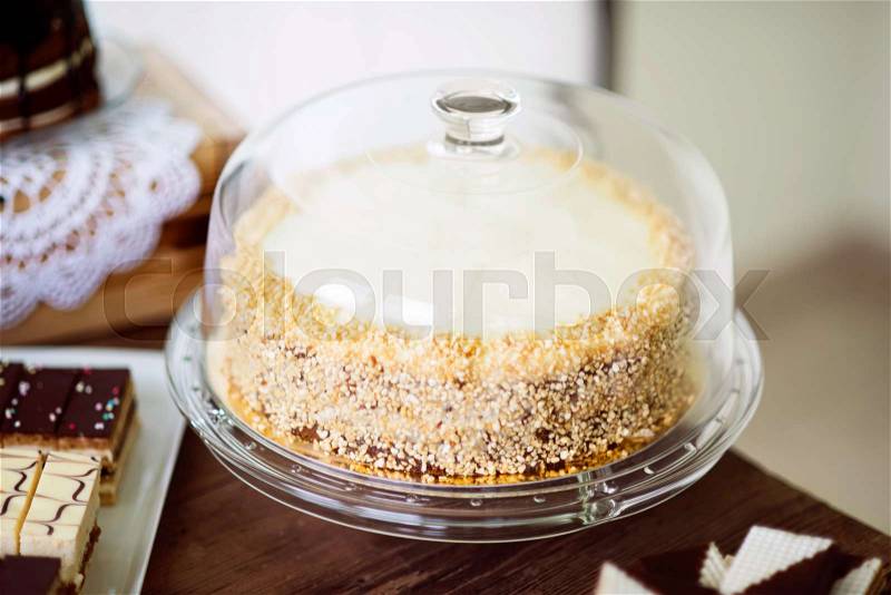Carrot cake with nuts and glaze on glass cake stand. Candy bar with various cakes. Studio shot, stock photo