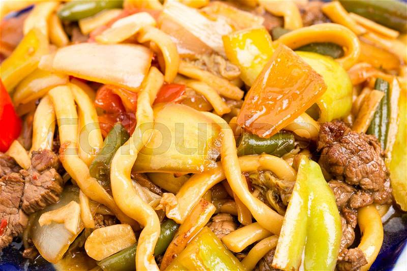 Baked lamb with wheat noodles and stewed vegetables on authentic oriental plate. Macro. Photo can be used as a whole background, stock photo