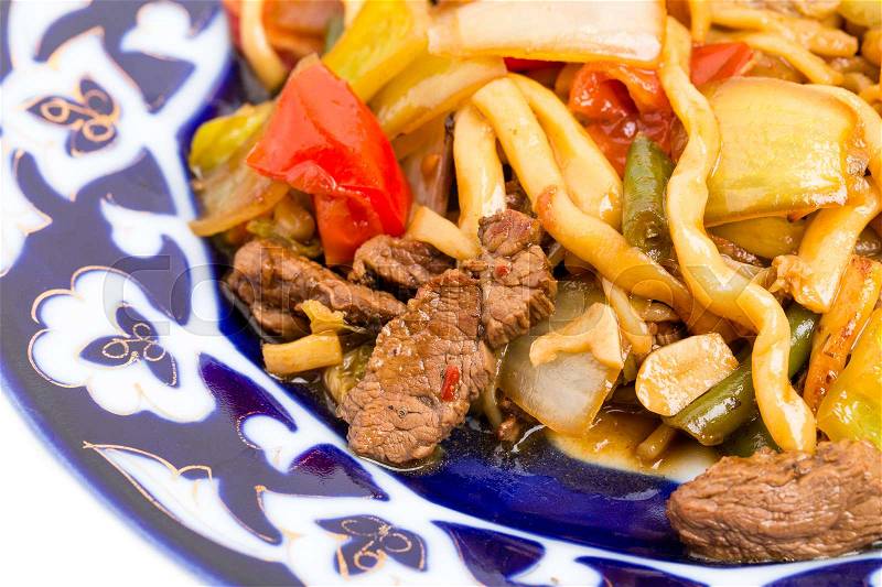 Baked lamb with wheat noodles and stewed vegetables on authentic oriental plate. Macro. Photo can be used as a whole background, stock photo