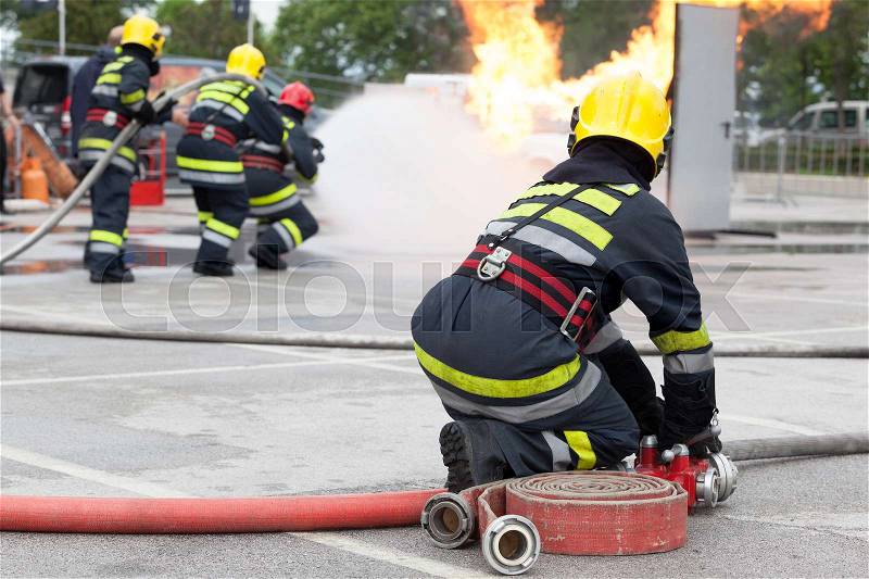 Firefighters spraying water in fire fighting training operation, stock photo