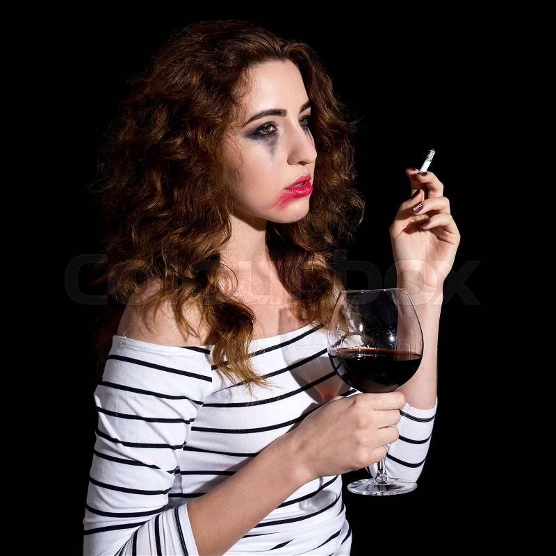 Depression - crying sad woman drinking wine and smoking isolated on black background, stock photo