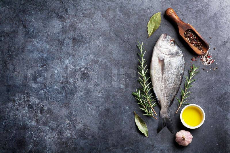 Raw fish cooking and ingredients. Dorado, herbs and spices. Top view with copy space on stone table, stock photo