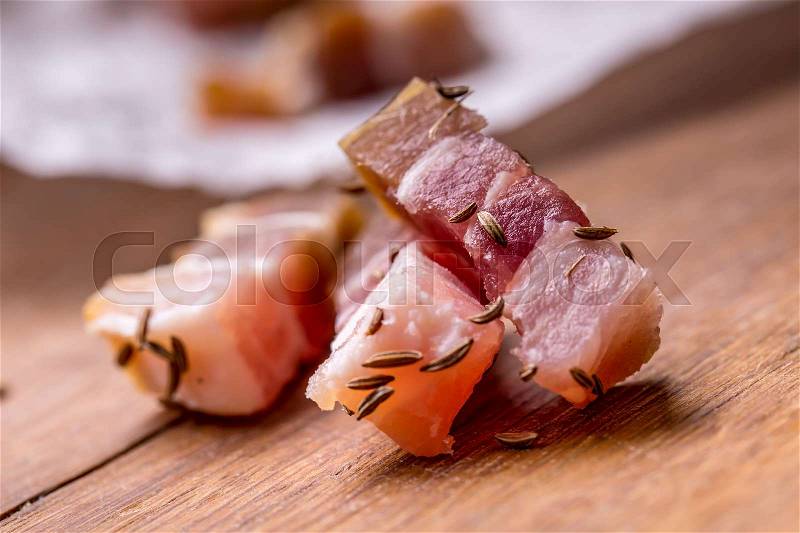Raw smoked bacon slices on wooden board with cumin and herbs, stock photo