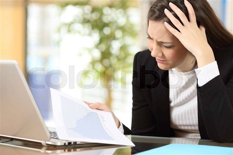 Worried businesswoman in bankruptcy watching decreased sales statistics in a paper document at office, stock photo