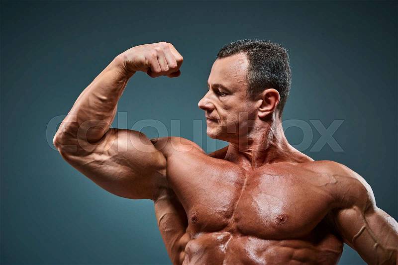 The torso of attractive male body builder on gray background, stock photo