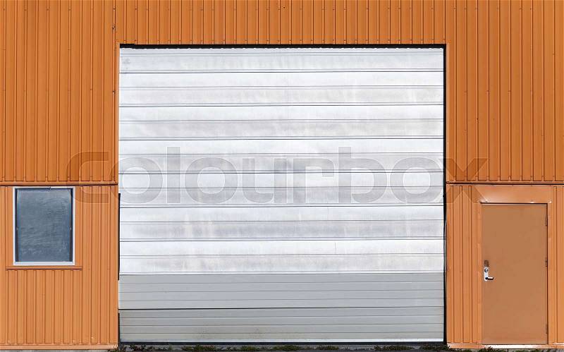 Red metal warehouse wall with closed gate, door and window, flat background photo texture, stock photo