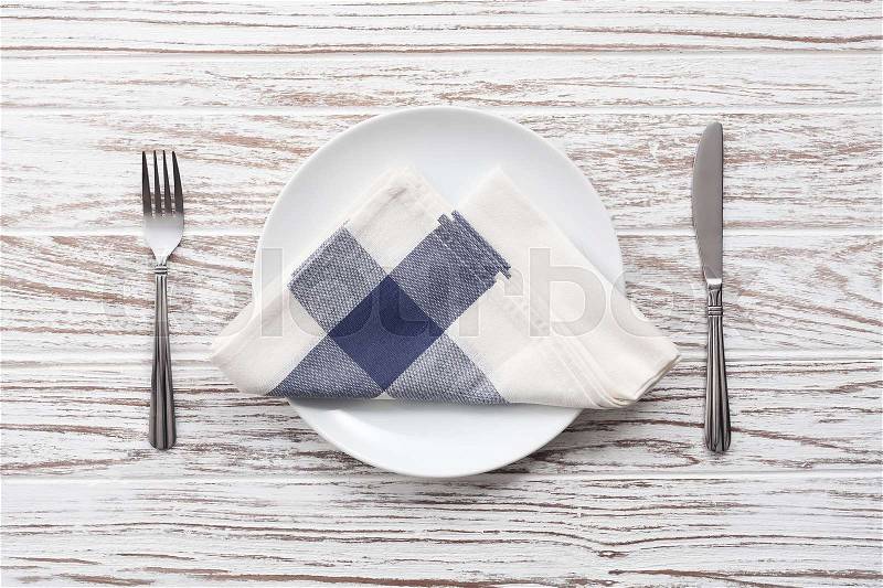 Empty plate napkin fork knife silverware white wooden table background still life vintage flat lay, stock photo