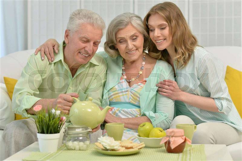 Cute family portrait , adult daughter with senior parents drinking tea, stock photo
