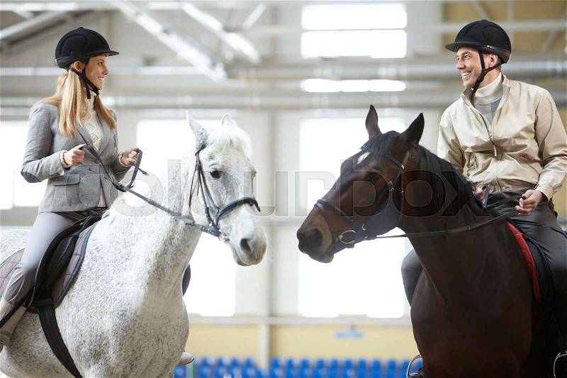 Romantic moment: happy young woman and man sitting on the horses, stock photo