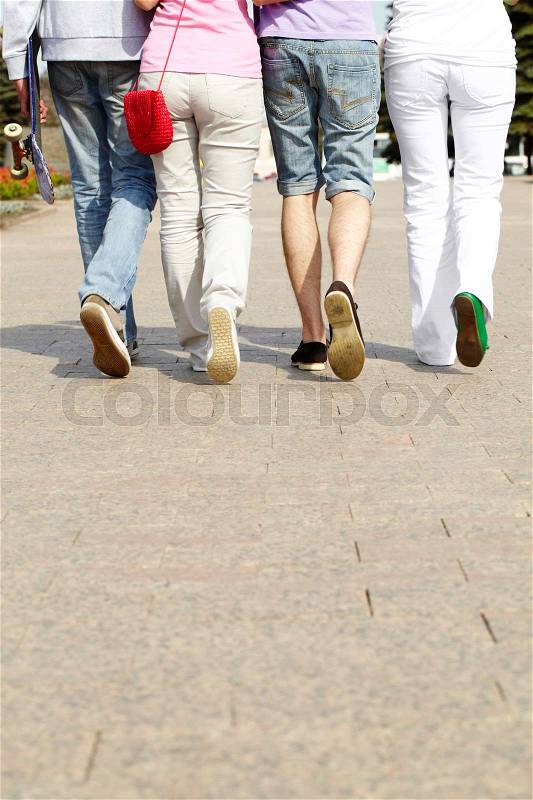 Legs of four friends walking together, stock photo