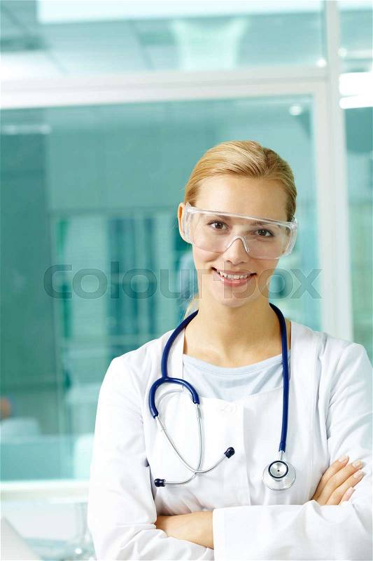 Portrait of a young doctor in medical goggles looking at camera and smiling, stock photo