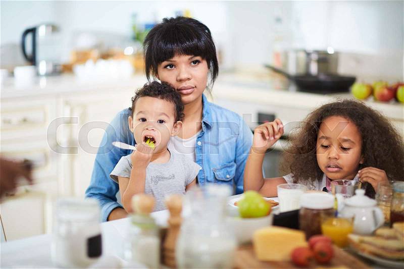 Mixed-race family having breakfast in the kitchen, stock photo
