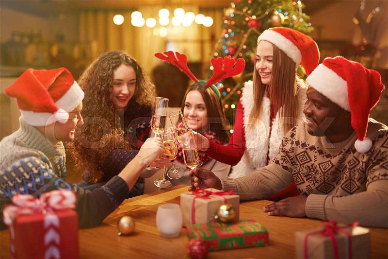 Friends making toast with champagne by Christmas table, stock photo