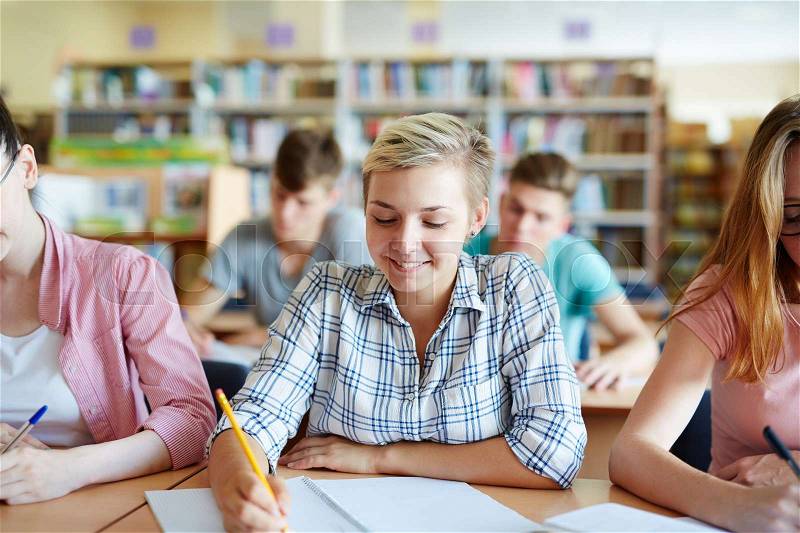 Students of college writing essay at lesson, stock photo