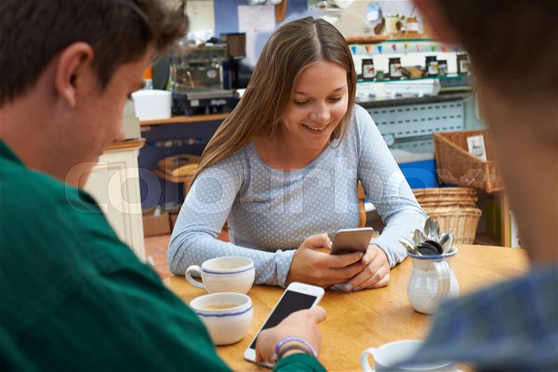 Group Of Teenage Friends Meeting In Cafe And Using Mobile Phones, stock photo