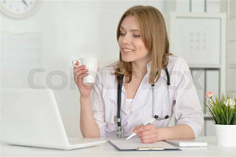 Portrait of cute female doctor with laptop, stock photo