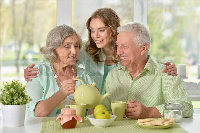 Cute family portrait , adult daughter with senior parents drinking tea, stock photo