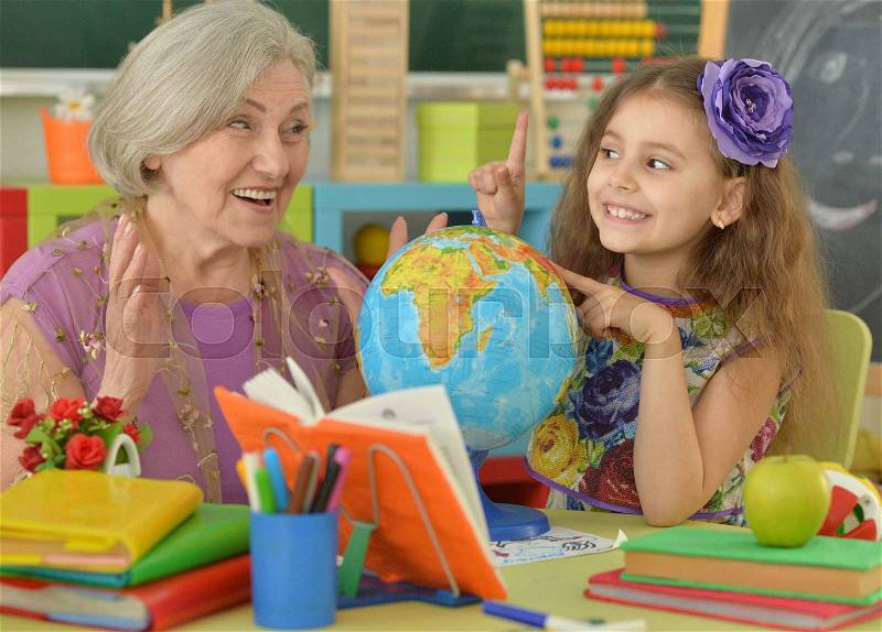Cute little girl making homework with granny, stock photo