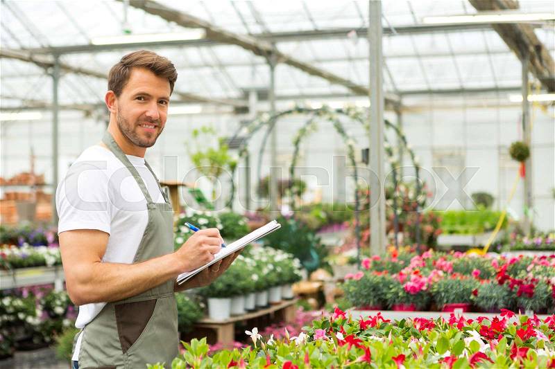 View of a Young attractive man writing notes at the plants nursery , stock photo