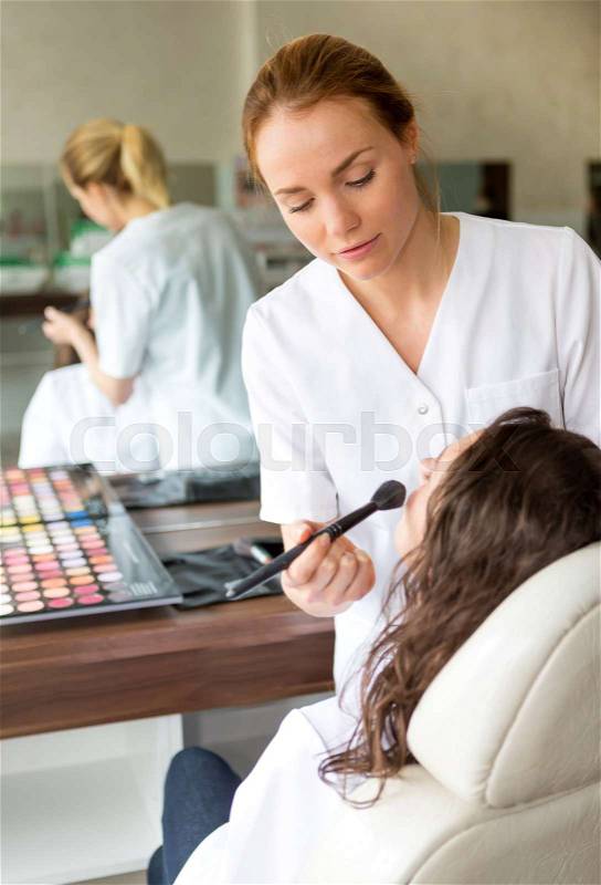 View of Two young beautician students working during make up classes, stock photo
