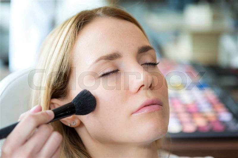 View of a Professional beautician make up the face of a beautiful woman, stock photo