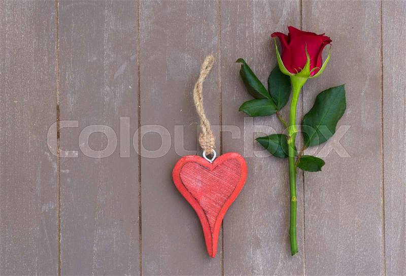 Still life with fresh rose flower and heart, top view, copy space on wooden table, stock photo