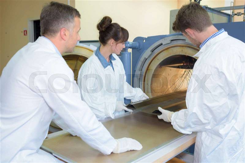 Workers placing metal into oven, stock photo