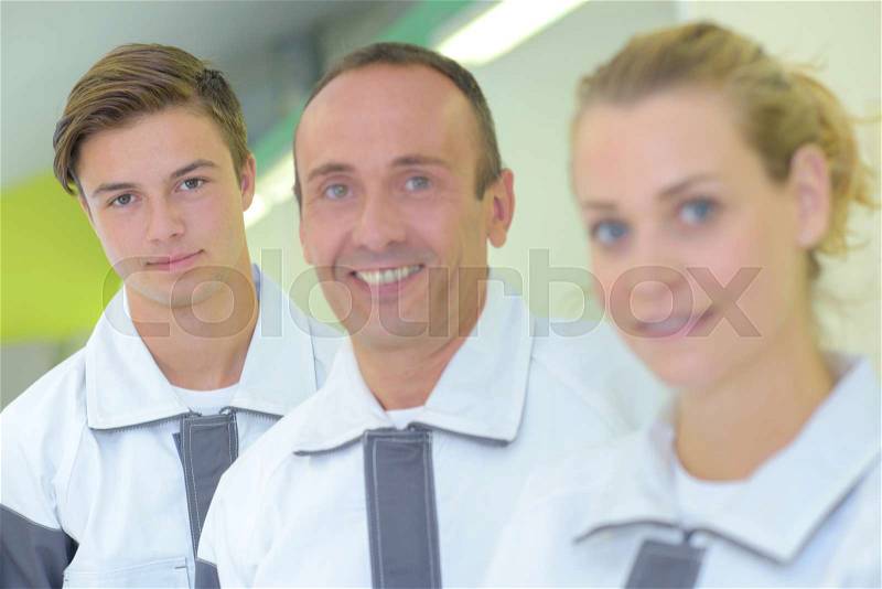 Portrait of three workers in matching coveralls, stock photo