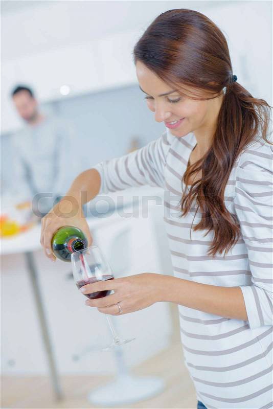 Woman pouring red wine into a glass, stock photo