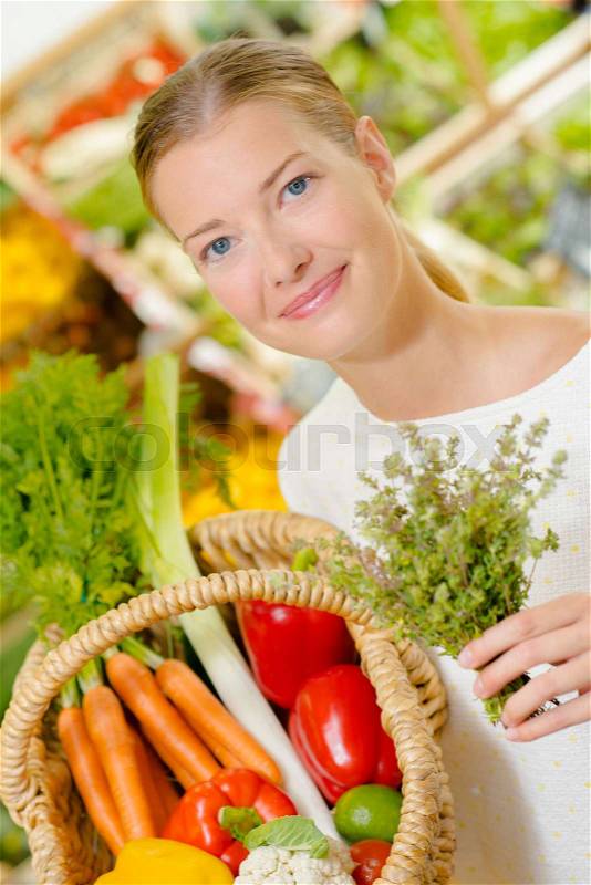 Lady adding herbs to purchases in a basket, stock photo