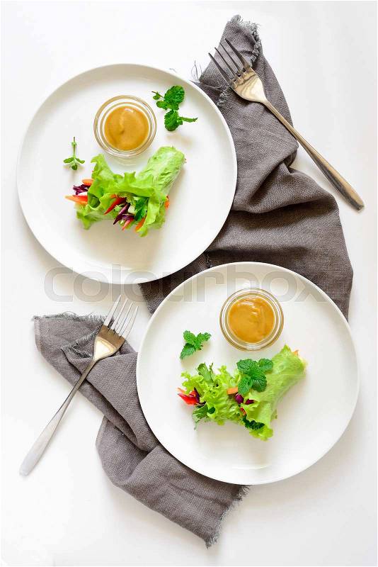 Lettuce vegetarian wraps or rolls stuffed with freshly chopped juicy vegetables and herbs, served with sauce and decorated with fresh mint leaves, view from above, stock photo