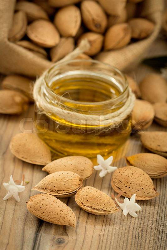 Almond oil and almonds on an old wooden background, selective focus, stock photo