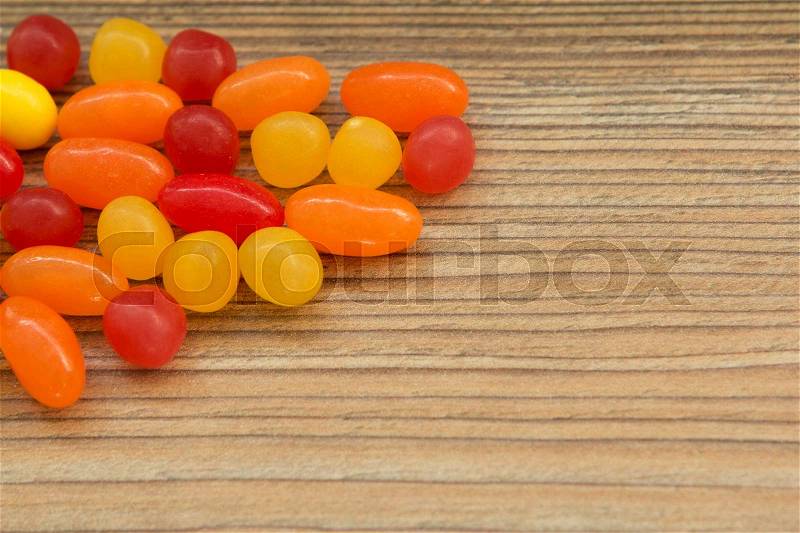 Colorful jelly beans shaped a frame to write your text on a wooden background, stock photo