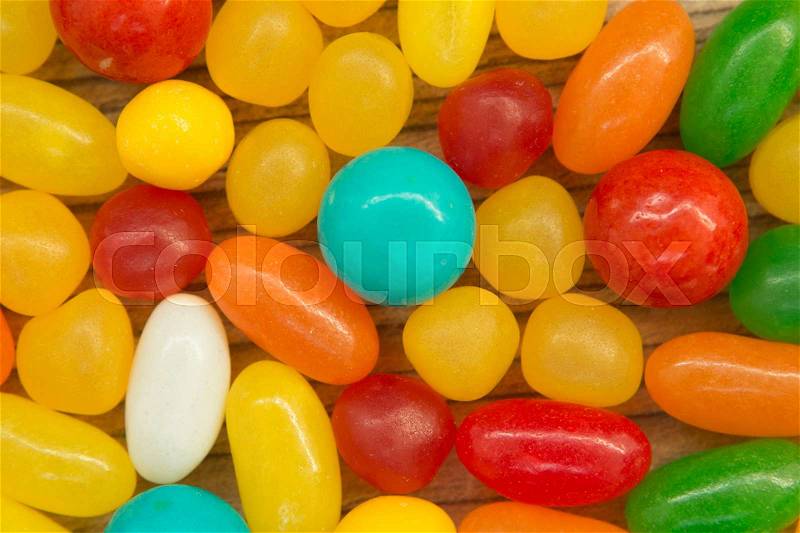 Colorful jelly beans of different sizes close to wallpaper, stock photo
