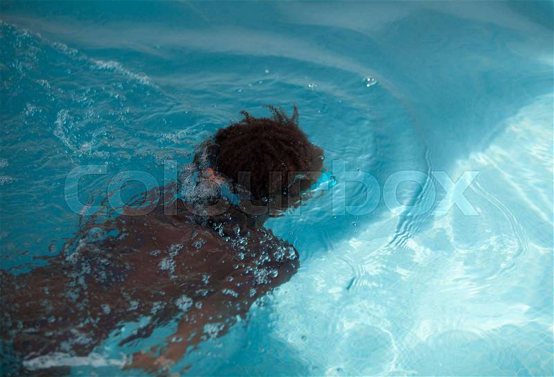 Small African American child with goggles in the pool, stock photo