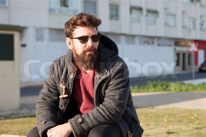 Young men with hipster look sitting on a bench in street, stock photo